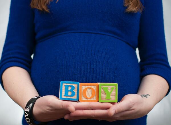 pregnant woman holding blocks that spell boy