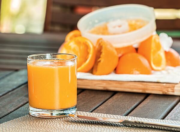 glass of orange juice with a bowl of orange slices