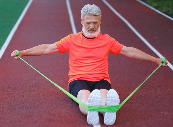 man sitting on track with resistance cords